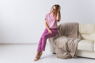 Young attractive woman dressed in beautiful colorful pajama posing as a model in her living room. Comfortable sleepwear, home relaxation and female fashion concept.