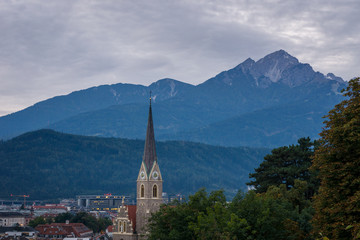  A church tower with beautiful mountains in the background in Innsbruck, Austria