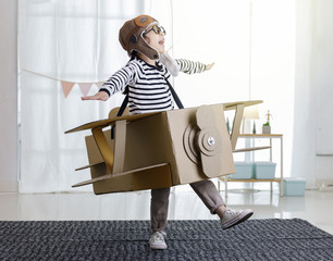 Asian little child girl playing with cardboard toy airplane handicraft isolated in home with copy space for your text, Creative with family and dreaming of flying concept - Powered by Adobe