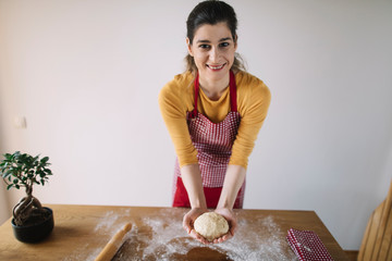 Cheerful woman holding dough ready for baking
