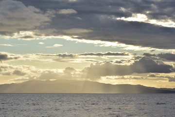 Fototapeta premium Sunset sky with clouds and mountains by the sea