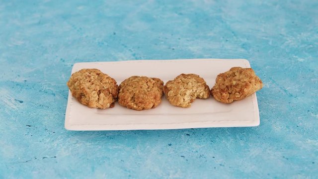 vegan almond and oats cookies and hand grabbing one and placing it back with a bite