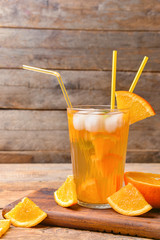 Glass of tasty cold ice tea on wooden background