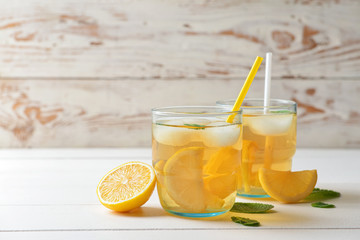 Glasses of tasty cold ice tea on white wooden background