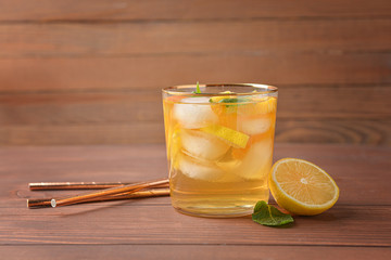 Glass of tasty cold ice tea on wooden background