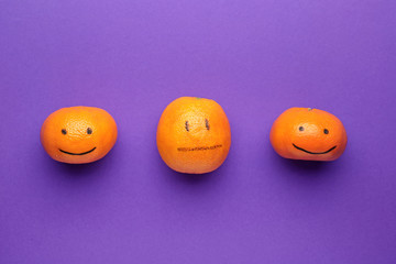 Naklejka premium One citrus fruit with drawn neutral face among happy ones on color background. Concept of depression