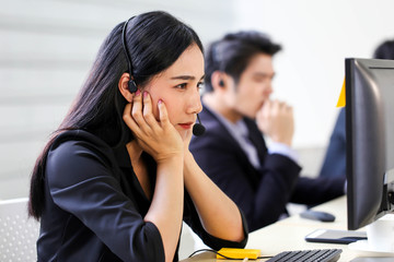 Beautiful asian woman Serious call center operator in wireless headset talking with customer,in customer support service.