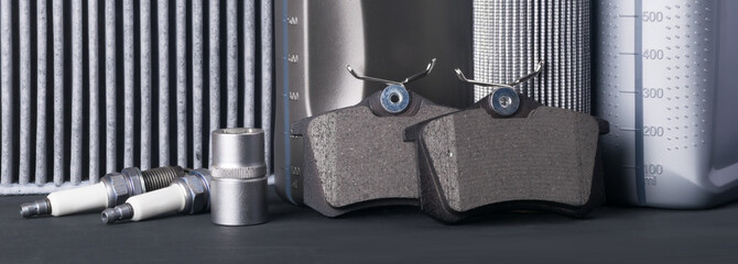 consumables for car maintenance, on a black table, brake pads, spark plugs and engine oil, close-up