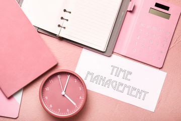 Alarm clock with stationery and text TIME MANAGEMENT on color background