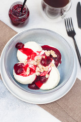 Cottage cheese pancakes with cherry sauce and nuts in grey bowl. Close up. Healthy breakfast concept.