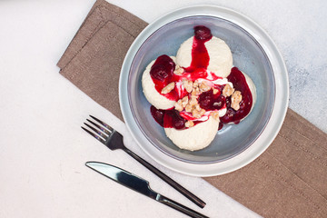 Cottage cheese pancakes with cherry sauce and nuts in grey bowl. Close up. Healthy breakfast concept.