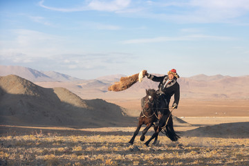 Kazakh eagle hunter after winning a traditional wrestling match. Two wrestlers on horseback start...