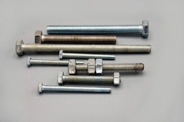 Metal screws and nuts isolated on gray background. New and shiny chrome screws and nuts. Copy space.