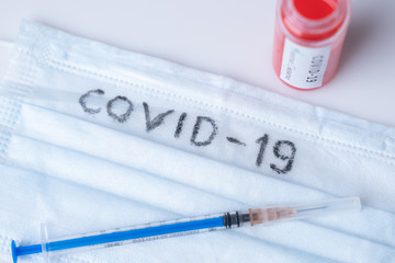 A medical mask, a syringe and a test tube with blood on a white background. The Inscription Covid 19