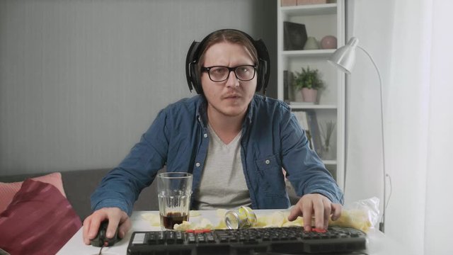 Young man playing video game at home feeling Upset after losing and showing indecent gesture