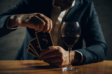 Close up of hands playing card and drinking wine.
