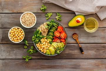 Veggie bowl. Vegetable salad with quinoa, avocado, tomato, spinach and chickpeas - on wooden table. Top view