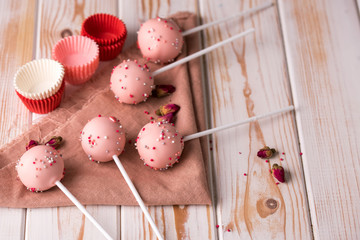 Dessert on a stick. Pink cake pops with a sprinkle on a wooden background.
