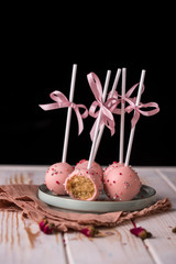 Cake pops in pink cream lie on a beautiful plate. Delicious close-up dessert.