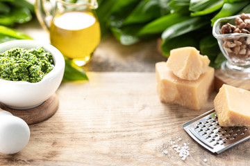 Wild leek pesto with olive oil and parmesan cheese in a white ceramic mortar on a wooden table. Useful properties of ramson. Copy space.