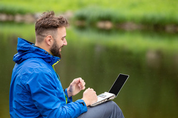 Young man with a laptop on the nature