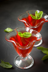 Red jelly  dessert with mint leaves , black background.Red juice
