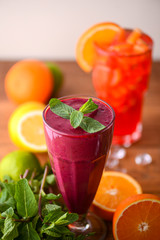 Two tropical mixed drinks, orange and raspberries cocktails served on light wooden table.