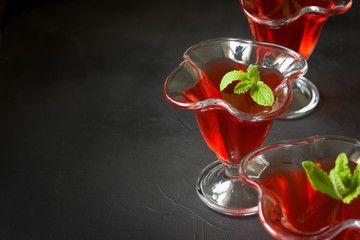 Red jelly  dessert with mint leaves , black background.Red juice