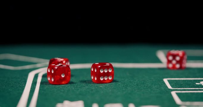 Close up of rolling dice on green poker table with black background shot in 4k supel slow motion