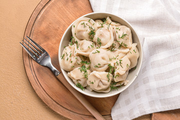 Bowl with tasty dumplings on color background