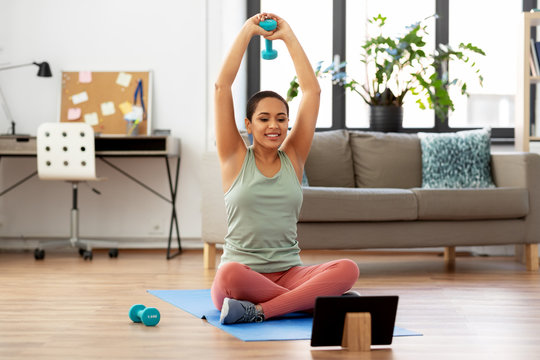fitness, sport and healthy lifestyle concept - happy smiling african american woman with tablet pc computer and dumbbells exercising at home