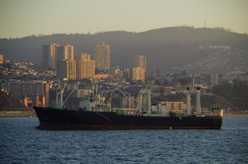 Fishing boat or ship with skyline of Valparaiso, Chile in background during twilight