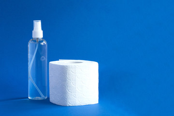 Bottle of sanitizer and white toilet paper on the blue background