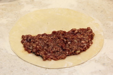 homemade Chebureki. Round dough piece with minced meat filling