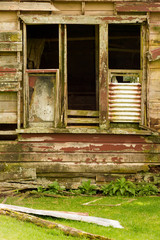 Fototapeta na wymiar The empty windows of a derelict, abandoned wooden farmhouse
