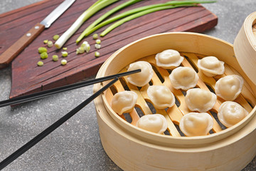 Steamer with tasty dumplings on grey background