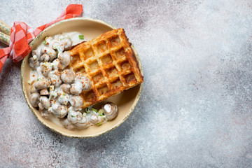 Belgian waffle with roasted champignons, above view on a beige stone background, horizontal shot with copyspace