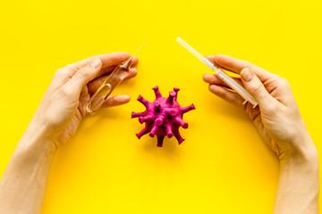 Corona virus Covid-19 - creating vaccine concept, with syringe and hands - on yellow background top-down