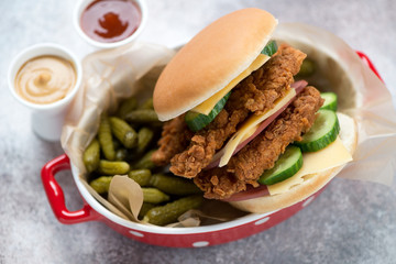 Double burger with fried chicken strips, pickles and dips in a red serving tray, elevated view, horizontal shot