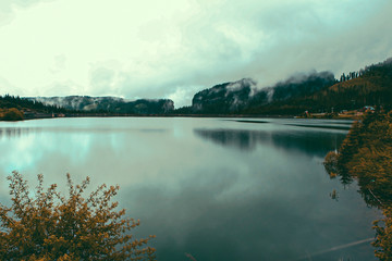 Fototapeta premium Panorama Mountain Foggy Carpathian Mountains peaks on a foggy autumn morning and lake view. Bucegi Mountains, Romania Europe