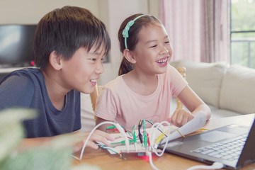 Mixed race young Asian children having fun learning coding together, learning remotely at home,...