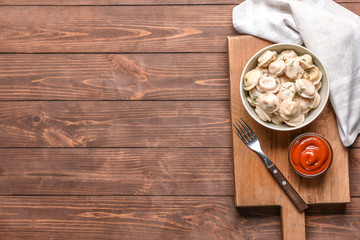 Bowl with tasty dumplings and sauce on table