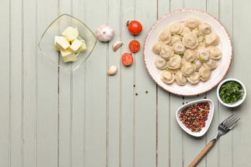 Plate with tasty dumplings, butter and spices on table