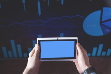 Businessman holding tablet and working in financial graphs in screen.