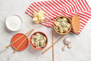 Bowls with tasty dumplings, butter and sauce on table