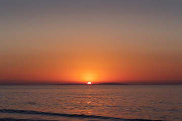 Sea coast at sunset, with the sun, wave, orange sky
