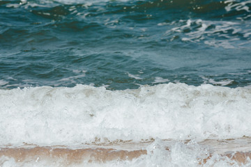 Blue sea wave with yellow sand on the shore