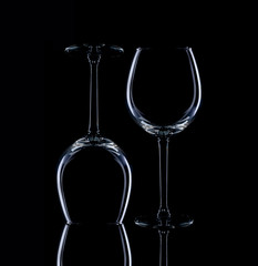Wine glasses of different shapes and a bottle on a black background.