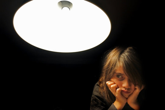 Upst girl looking away from camera in dark dedroom