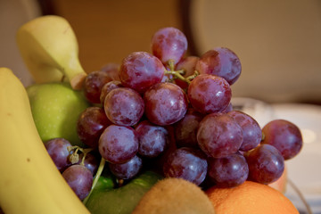 Wet fruits, partial with mirror image, slightly blurred. Bright clear colors. Space for text. selective focus. Red grapes on fruit in the plate.Fresh red grapes on a reflecting plate.